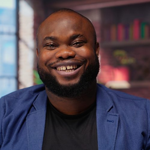 Teleworker at home office editing documents on his personal laptop, submitting reports and files before deadline. Black freelancer managing digital paperwork within the work platform. Camera b.